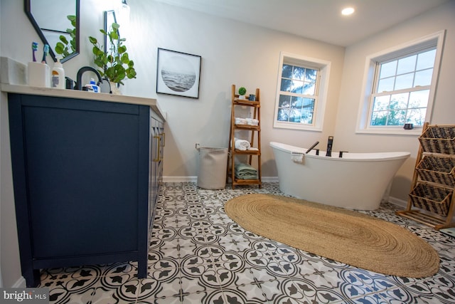 bathroom with a freestanding tub, baseboards, and recessed lighting
