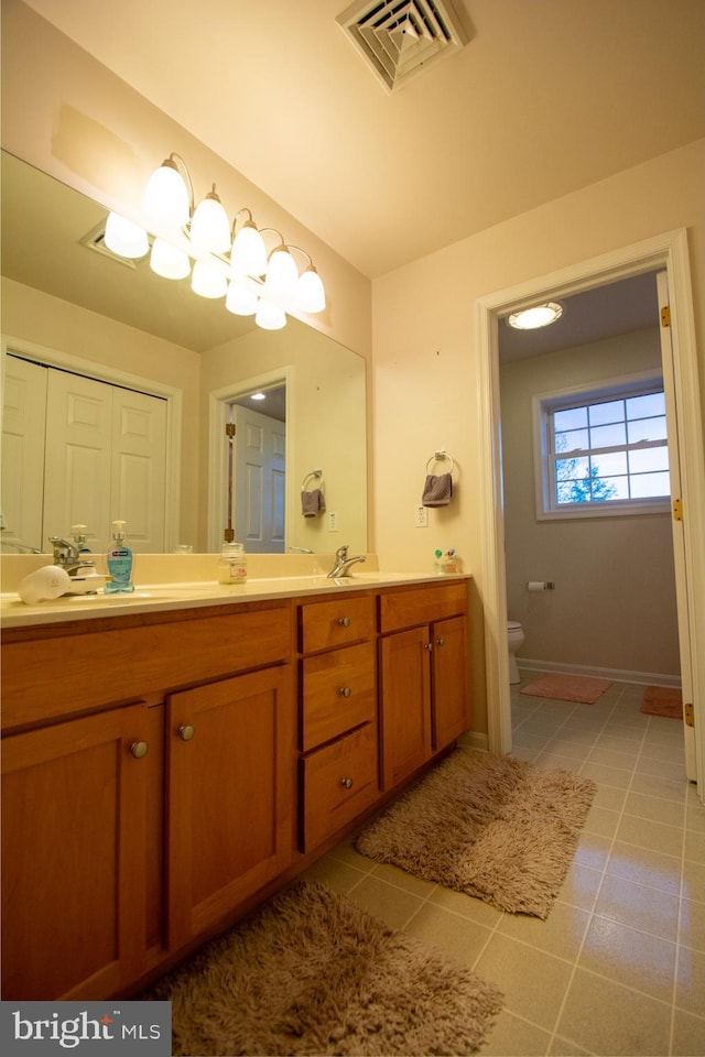 full bathroom featuring toilet, double vanity, baseboards, and tile patterned floors