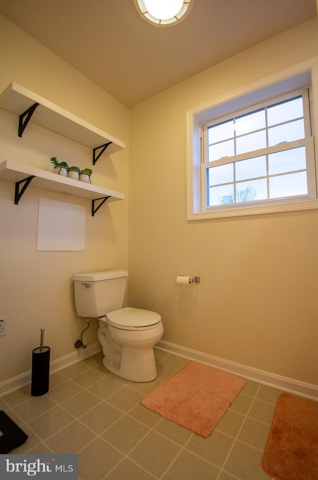 half bathroom with toilet, tile patterned floors, and baseboards