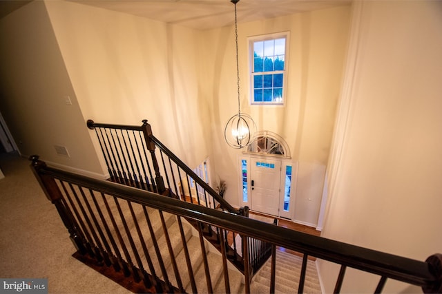 staircase featuring a chandelier, carpet, and baseboards