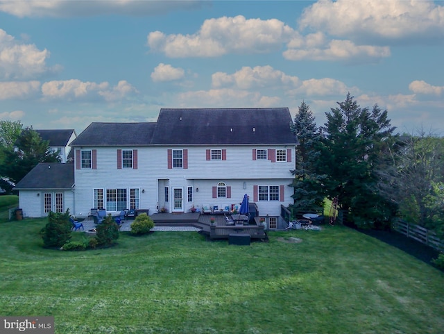 rear view of house featuring a lawn and a wooden deck
