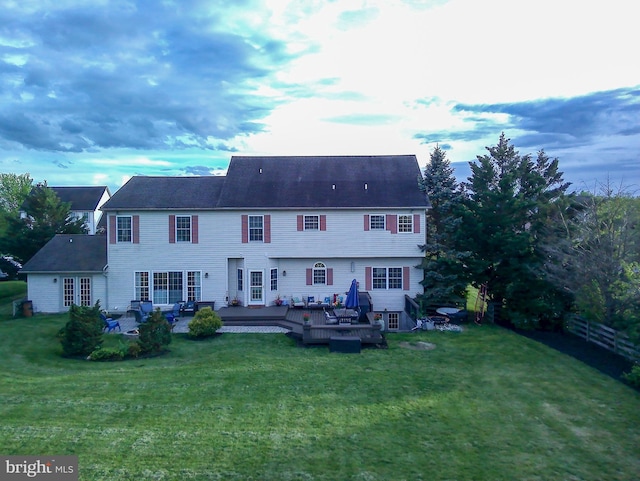 back of property with a lawn and a deck