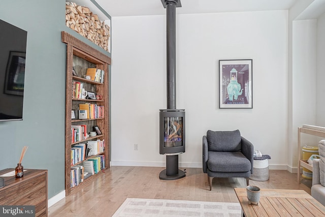 sitting room with wood finished floors, baseboards, and a wood stove