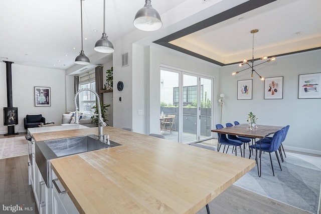 kitchen with a sink, butcher block counters, dark wood-style flooring, and a wood stove