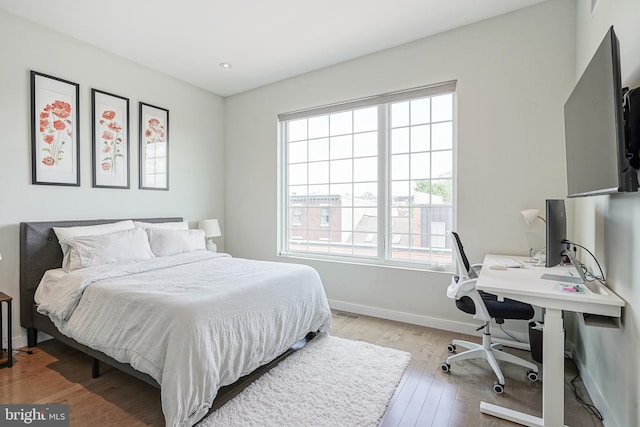 bedroom featuring multiple windows, light wood-style flooring, an office area, baseboards, and recessed lighting