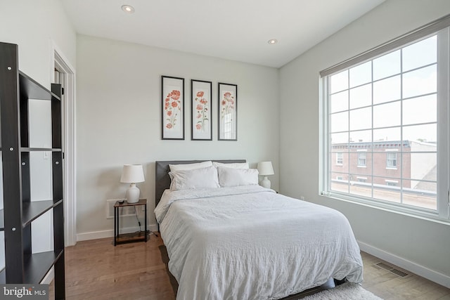 bedroom featuring multiple windows, baseboards, wood finished floors, and recessed lighting