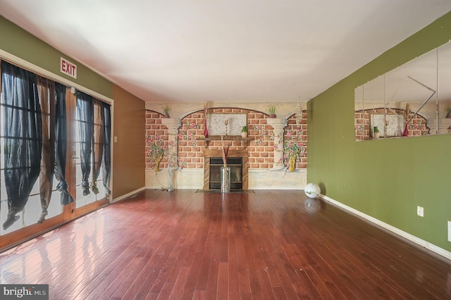 unfurnished living room featuring a fireplace, hardwood / wood-style flooring, and baseboards
