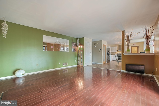unfurnished living room featuring wood-type flooring and baseboards