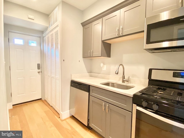 1715 Montello Ave NE, Washington, DC 20002 - kitchen featuring appliances with stainless steel finishes, a sink, gray cabinetry, and light wood-style flooring