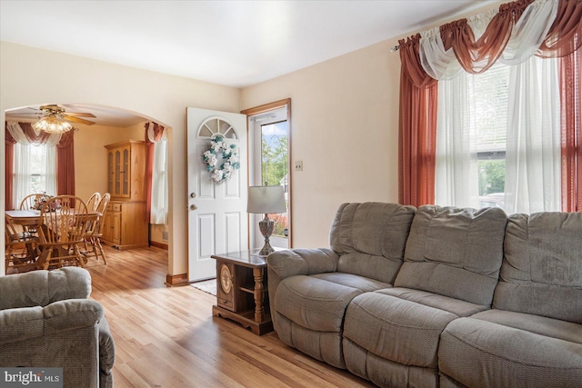 living room featuring plenty of natural light, arched walkways, and light wood-style flooring