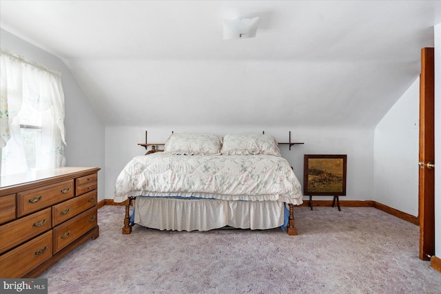 bedroom featuring vaulted ceiling, light colored carpet, and baseboards