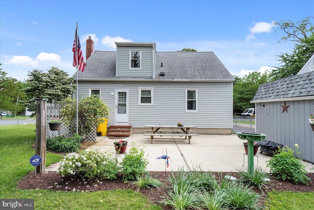 back of house with a patio, entry steps, roof with shingles, a chimney, and a yard
