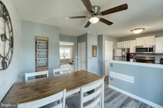 dining space with ceiling fan, wood finished floors, and baseboards