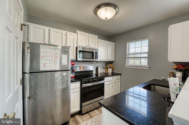 kitchen featuring stainless steel appliances, white cabinetry, backsplash, and light wood finished floors