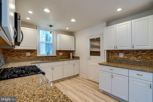 kitchen featuring a sink, white cabinets, light wood-type flooring, decorative backsplash, and recessed lighting