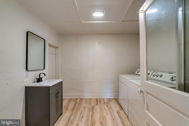 laundry area with a sink, washing machine and clothes dryer, light wood-style floors, and baseboards