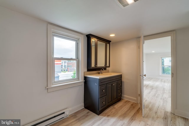 bathroom featuring baseboard heating, wood finished floors, vanity, and baseboards