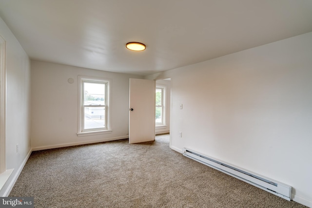 unfurnished room with a baseboard heating unit, carpet floors, and baseboards
