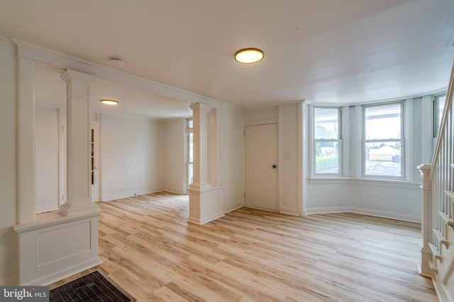 unfurnished room with decorative columns, light wood-style floors, baseboards, a smoke detector, and stairway