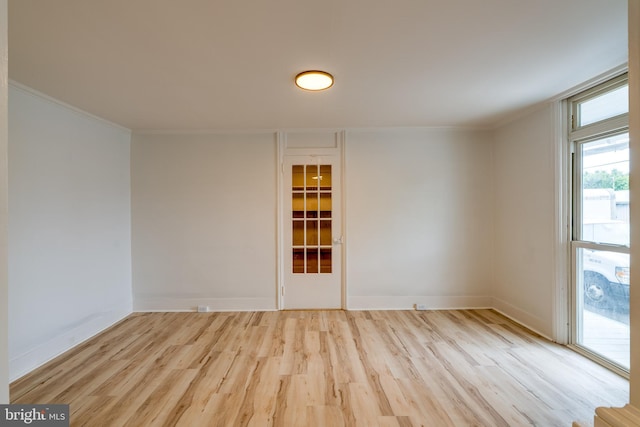 unfurnished room featuring wood finished floors, crown molding, and baseboards