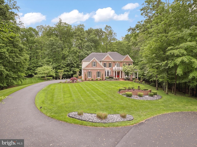 8197 Cottage Rose Ct, Fairfax Station, VA 22039 - georgian-style home featuring a front lawn, asphalt driveway, and a view of trees