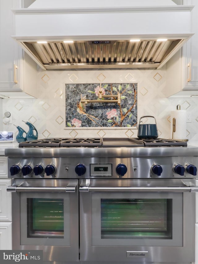 8197 Cottage Rose Ct, Fairfax Station, VA 22039 - detailed view of range with two ovens, custom range hood, white cabinets, and tasteful backsplash
