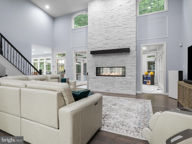 8197 Cottage Rose Ct, Fairfax Station, VA 22039 - living area with a high ceiling, healthy amount of natural light, wood finished floors, a stone fireplace, and baseboards