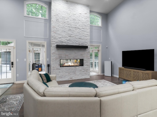 8197 Cottage Rose Ct, Fairfax Station, VA 22039 - living area with a towering ceiling, wood finished floors, a stone fireplace, and baseboards