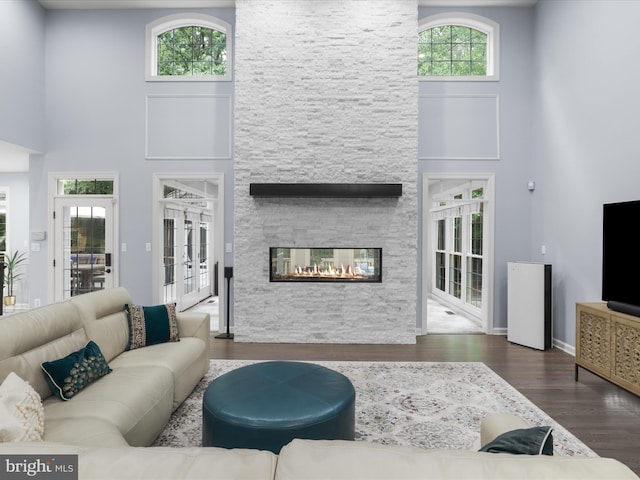 8197 Cottage Rose Ct, Fairfax Station, VA 22039 - living area with wood finished floors, a towering ceiling, french doors, a stone fireplace, and baseboards
