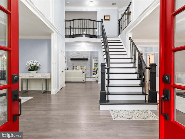 8197 Cottage Rose Ct, Fairfax Station, VA 22039 - foyer with crown molding, wood finished floors, stairs, a fireplace, and a high ceiling