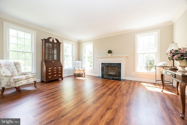living area featuring plenty of natural light, wood finished floors, baseboards, and ornamental molding