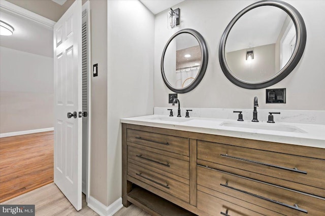 full bath with wood finished floors, baseboards, and double vanity