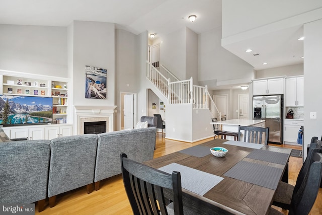 12001 Market St Unit 441, Reston, VA 20190 - dining space featuring stairway, high vaulted ceiling, light wood-type flooring, a fireplace, and recessed lighting