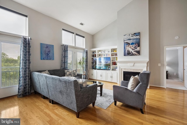 12001 Market St Unit 441, Reston, VA 20190 - living room featuring high vaulted ceiling, light wood-type flooring, a glass covered fireplace, and baseboards