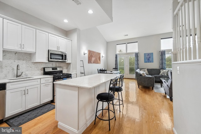 12001 Market St Unit 441, Reston, VA 20190 - kitchen featuring stainless steel appliances, a sink, light wood-style floors, a center island, and tasteful backsplash