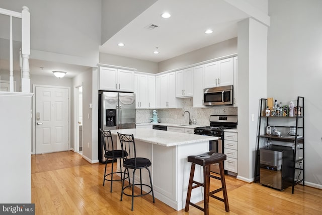 12001 Market St Unit 441, Reston, VA 20190 - kitchen with stainless steel appliances, light wood-style floors, a breakfast bar area, white cabinets, and recessed lighting