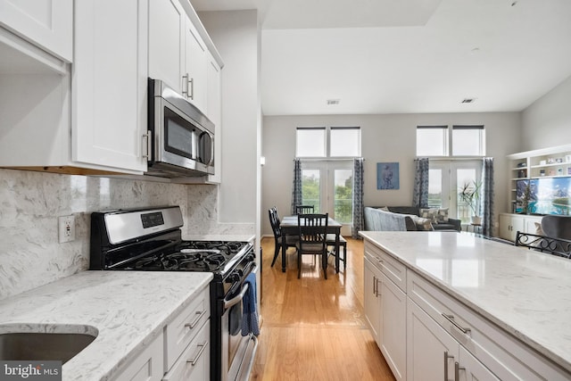 12001 Market St Unit 441, Reston, VA 20190 - kitchen featuring stainless steel appliances, light wood-style flooring, white cabinetry, and light stone counters
