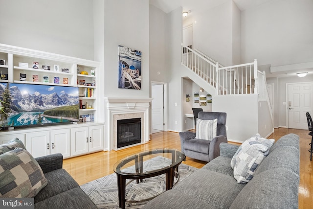 12001 Market St Unit 441, Reston, VA 20190 - living area featuring a high ceiling, stairway, light wood-type flooring, a fireplace, and baseboards