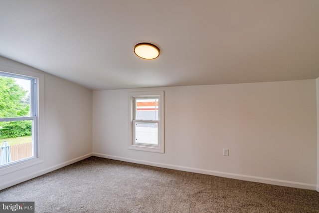 spare room featuring carpet floors, lofted ceiling, baseboards, and healthy amount of natural light