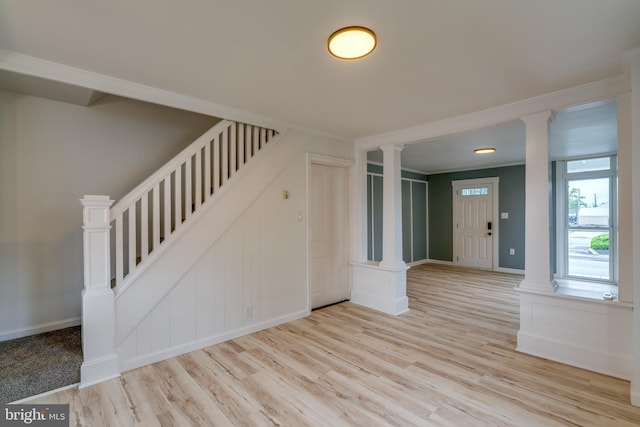 unfurnished living room featuring decorative columns, a decorative wall, wood finished floors, and stairs