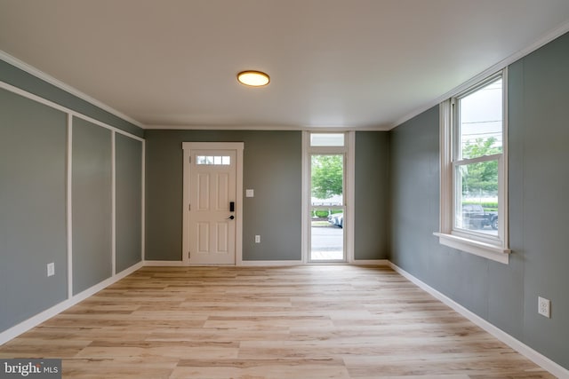foyer entrance featuring ornamental molding, light wood-style flooring, and baseboards