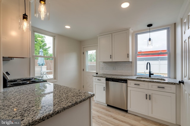 kitchen featuring stainless steel dishwasher, a sink, light stone counters, light wood-type flooring, and tasteful backsplash