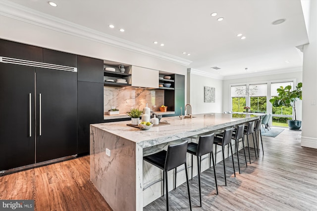 kitchen featuring open shelves, a spacious island, a breakfast bar area, light wood-type flooring, and modern cabinets