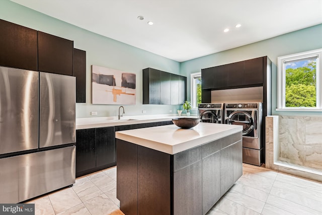 kitchen with freestanding refrigerator, washer and dryer, light countertops, light marble finish flooring, and a sink