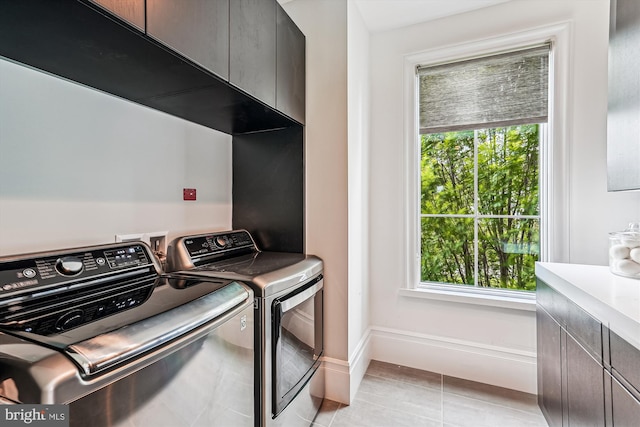 laundry room with cabinet space, washer and dryer, baseboards, and healthy amount of natural light