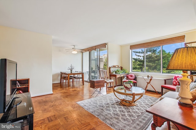 living area featuring a ceiling fan and baseboards