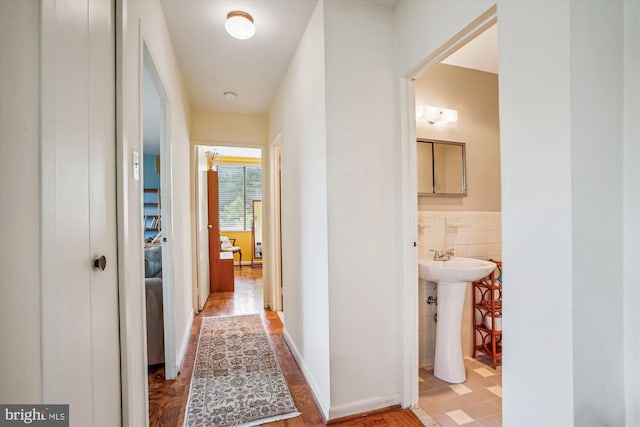 corridor with tile walls and a sink