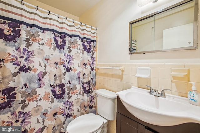 full bath featuring toilet, wainscoting, vanity, tile walls, and a shower with shower curtain