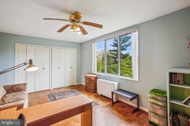 living area with baseboards and ceiling fan