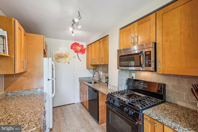 kitchen featuring black appliances, a sink, light stone countertops, and light wood-type flooring